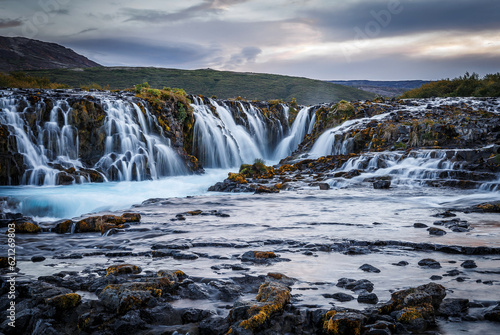 Scenic image of Iceland. Incredible nature landscape. Stunning view of Bruarfoss Waterfall. Azure water flows over stones. Bright midnight sun of Iceland. Iceland is a most popular place of travel.