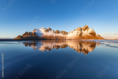 The incredible landscape of Vestrahorn in the south of Iceland. Beautiful back reflecting the mountain in the background.  photo