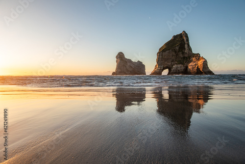 Wharariki beach famous from a background wallpaper during sunset with a wonderful reflection in the water on the beach sand 