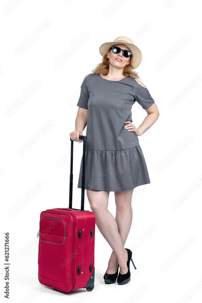 Happy woman in sunglasses, gray dress, hat and stiletto shoes stands with a red suitcase, isolated on a white background Happy woman in sunglasses, gray dress, hat and stiletto shoes stands with a red suitcase, isolated on a white background