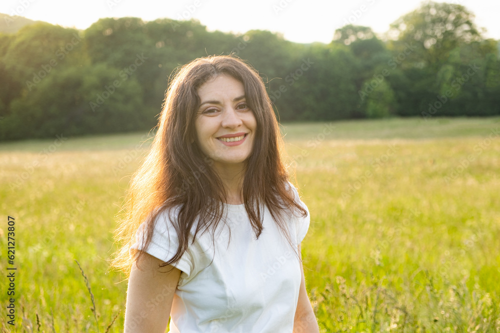 Portrait of a 35-year-old European woman smiling while looking at the camera while walking in nature in a field. Portrait of a 35-year-old European woman smiling while looking at the camera while walking in nature in a field.