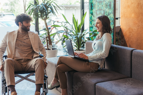 Handicapped male joking with his female colleague, laughing, working together in a good atmosphere