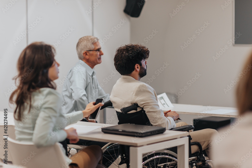 Obraz premium Male employee listening to business lecture with his different aged colleagues at the classroom
