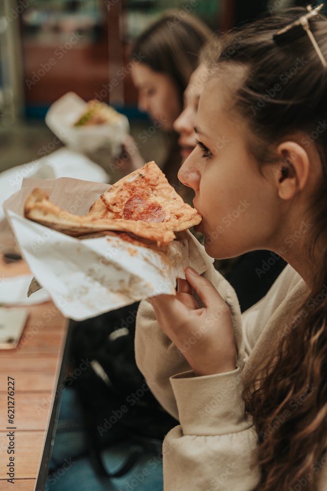 Close up shot of brunette girl biting a delicious slice of pizza Close up shot of brunette girl biting a delicious slice of pizza