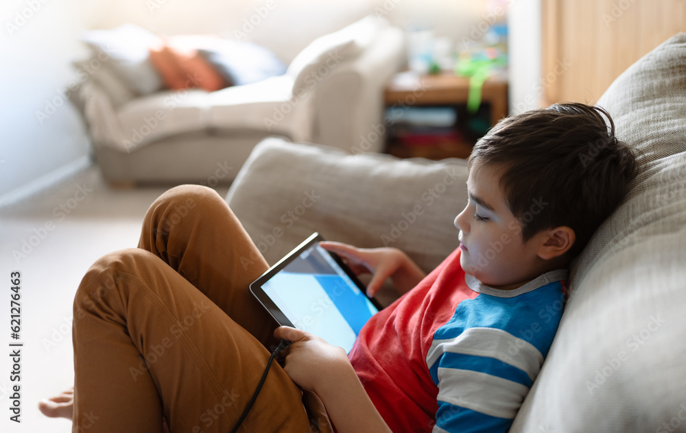 Preteen schoolboy doing homework with digital tablet in living room,Child using gadgets to study. Kid learns online from home,Education learning with new technology for kids. Preteen schoolboy doing homework with digital tablet in living room,Child using gadgets to study. Kid learns online from home,Education learning with new technology for kids.