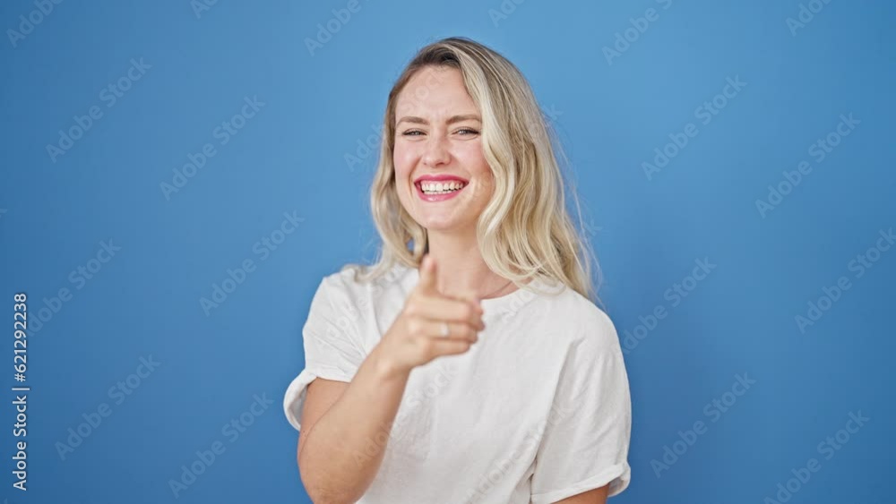 Young blonde woman smiling confident pointing to camera over isolated blue background Young blonde woman smiling confident pointing to camera over isolated blue background