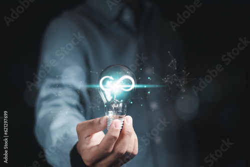 Businessman holding a glowing light bulb with infinity symbol, starting an idea for infinity business success.