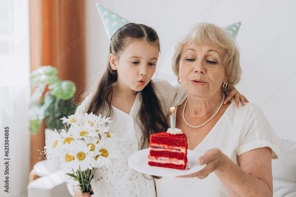 Happy smiling grandmother receives birthday greetings from granddaughter, little girl and senior