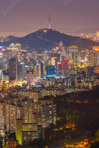 View of Namsan Seoul Tower surrounded by cityscape of Seoul illuminated with lights in the twilight view from Inwang mountain. Seoul, South Korea