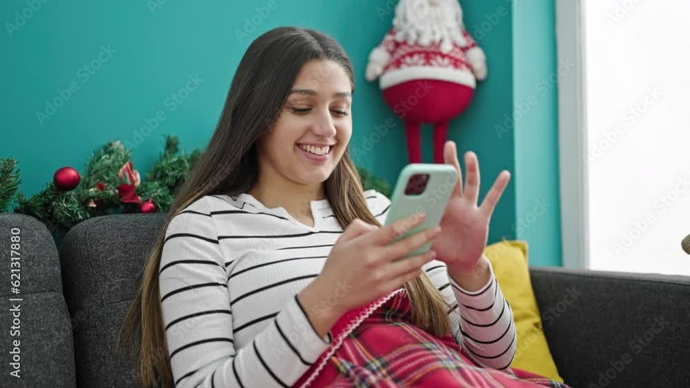 Young beautiful hispanic woman using smartphone celebrating christmas at home Young beautiful hispanic woman using smartphone celebrating christmas at home