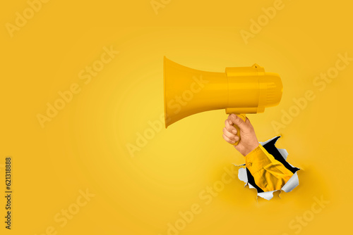 Loudhailer, hand holding megaphone breakthrough paper hole. Announcement, advertising, public hearing concept. Mockup design with loudspeaker, Torn background with blank empty space for copy space