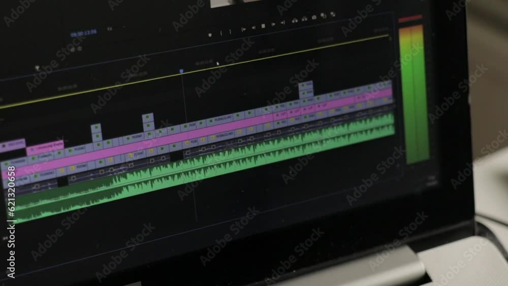Close up of a laptop with film and video editing software with a timeline and moving audio display. Selective focus. Close up of a laptop with film and video editing software with a timeline and moving audio display. Selective focus.