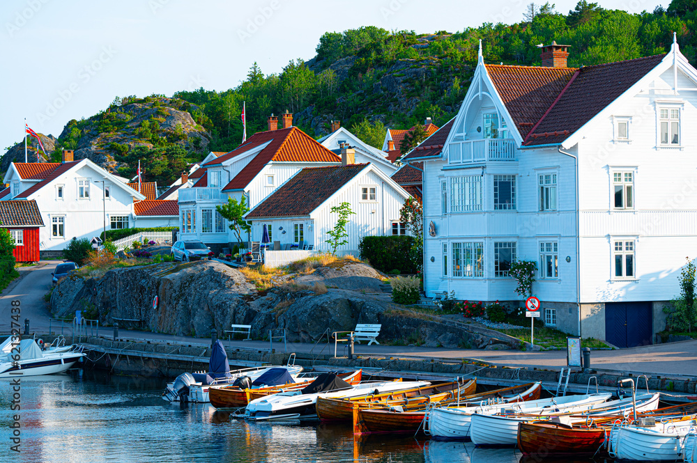 A beautiful village by the coast, white wooden houses with cute gardens and yachts in the bay