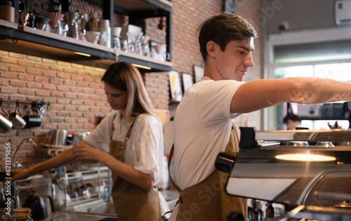Barista working in cafe. Portrait of young male barista standing behind counter in coffee shop.