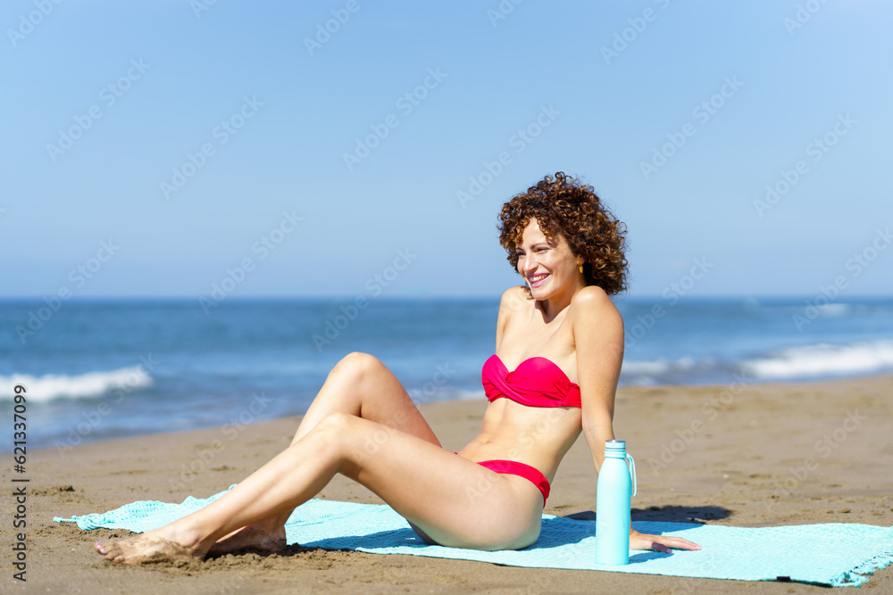 Happy woman in bikini on beach admiring view