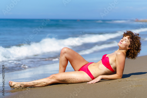 Sensual lady in bikini sunbathing on coast