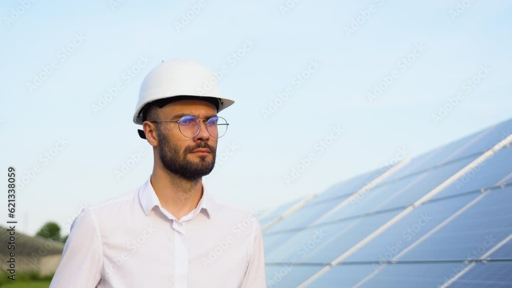 Solar power plant with engineer in protective helmet walking and examining photovoltaic panels. Concept of alternative energy and its maintenance Solar power plant with engineer in protective helmet walking and examining photovoltaic panels. Concept of alternative energy and its maintenance