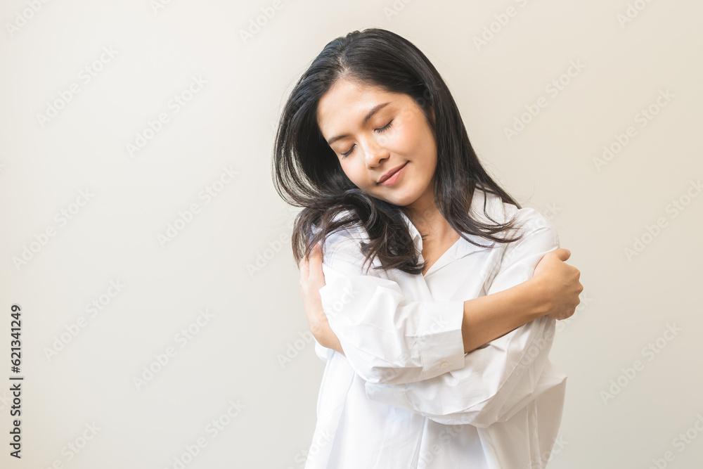 Smiling positive, hugging oneself happy asian young woman hands hug herself shoulders enjoy joyful, self hugging, self love and self care, face expression self esteem standing isolated on background. Smiling positive, hugging oneself happy asian young woman hands hug herself shoulders enjoy joyful, self hugging, self love and self care, face expression self esteem standing isolated on background.