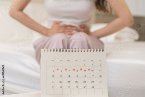Menstruation, period cycle day of monthly, hurt asian young woman, female hand in stomachache, suffer from PMS premenstrual, belly or abdomen pain on bed at home. Health problem Inflammation in body photo