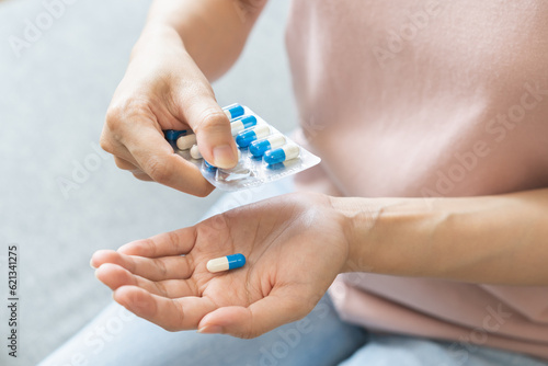 Obraz na plátně Sick ill asian young woman, girl hand taking tablet pill capsule out from blister pack, painkiller medicine from stomach pain, head ache, pain for treatment, take drug or vitamin at home, health care
