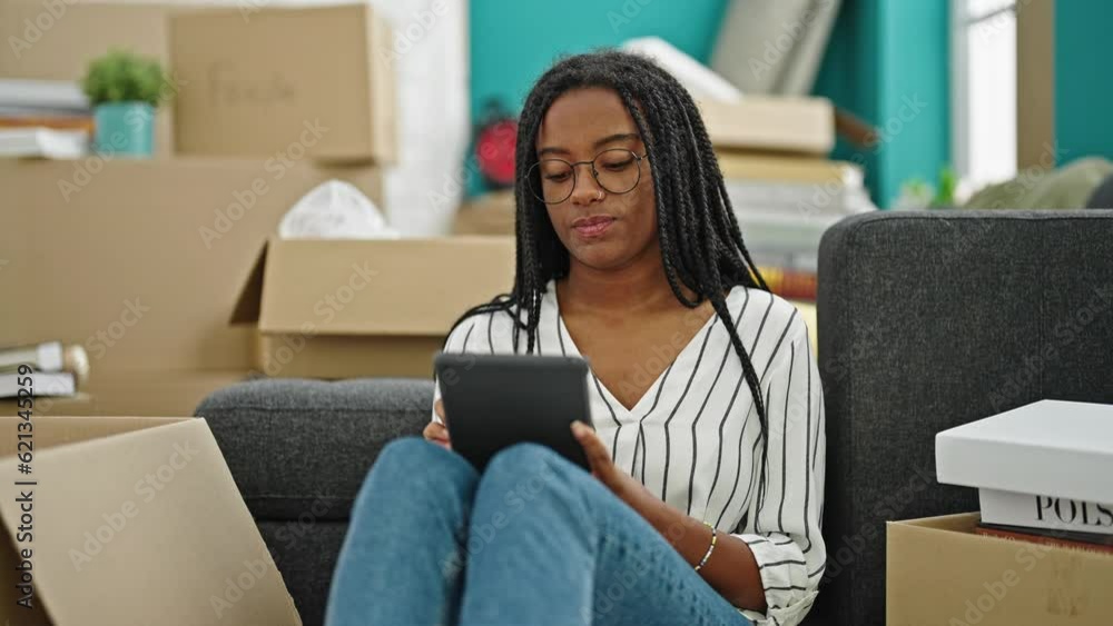 African american woman using touchpad sitting on floor at new home African american woman using touchpad sitting on floor at new home