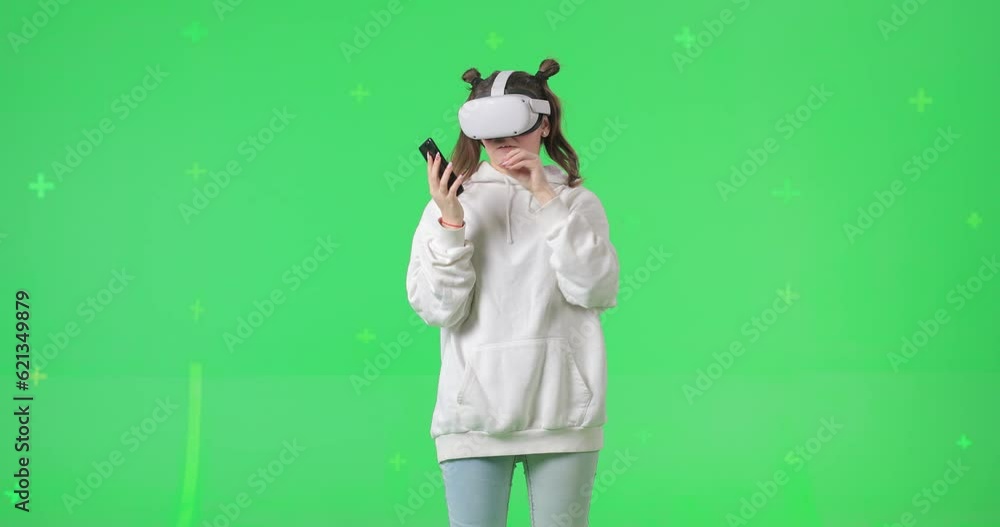 Shot on green screen background. VR or AR online at home. Cute girl in virtual reality headset. Woman clicks invisible buttons and pulls virtual sliders and interacts with mobile smart phone. Shot on green screen background. VR or AR online at home. Cute girl in virtual reality headset. Woman clicks invisible buttons and pulls virtual sliders and interacts with mobile smart phone.