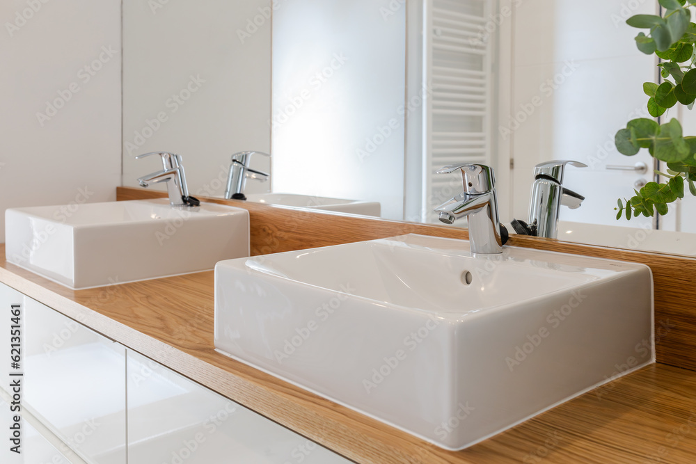 New water faucets and double sink with large mirror in a modern bathroom with natural light New water faucets and double sink with large mirror in a modern bathroom with natural light