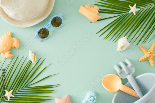 Kids' coastal relaxation period idea. Top view of beach toys, eyewear, panama hat, tropical leaves, starfish, seashells on pastel blue background with space for ads or message