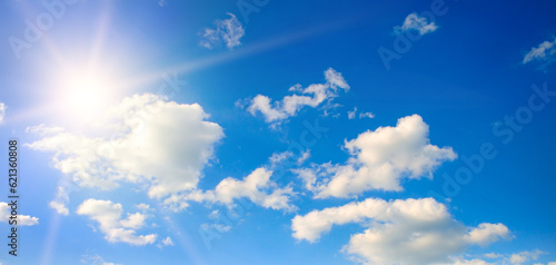Bright sun, blue sky and light clouds. Wide photo.