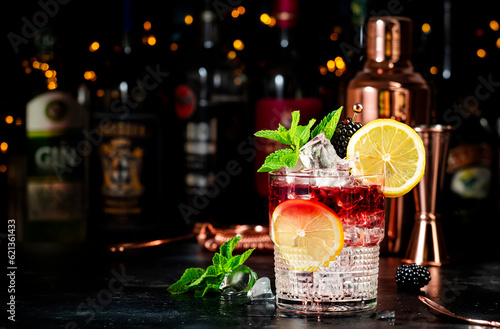 Photography Bramble alcohol cocktail drink with dry gin, liqueur, syrup, lemon juice, blackberry and ice