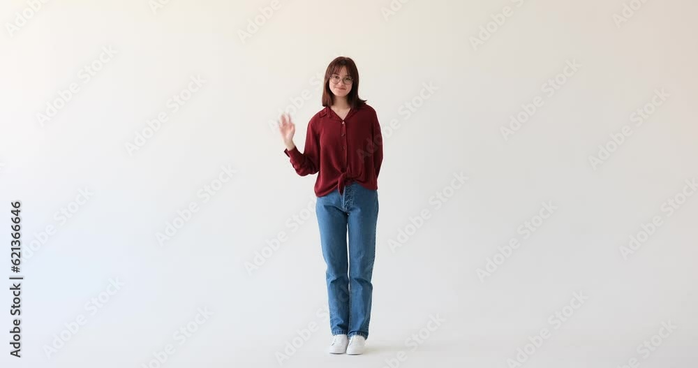 A satisfied Caucasian teen girl on white background. She exudes a sense of contentment as she extends a friendly greeting. With an infectious smile on her face, she energetically waves her hand. A satisfied Caucasian teen girl on white background. She exudes a sense of contentment as she extends a friendly greeting. With an infectious smile on her face, she energetically waves her hand.