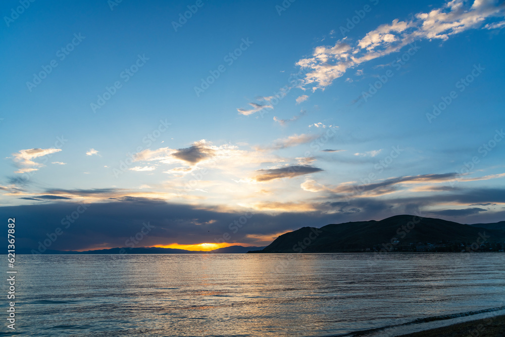 Fototapeta premium Beautiful bright sunset over the lake and mountains