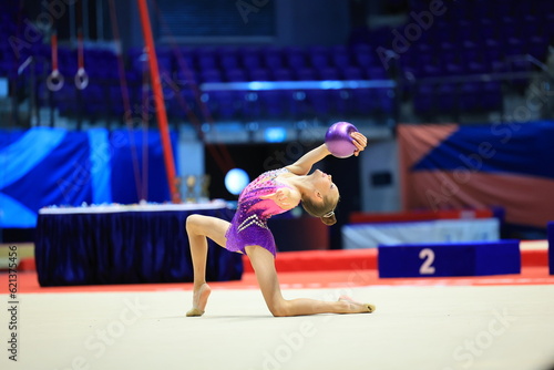 girl gymnast performs an exercise with a ball photo