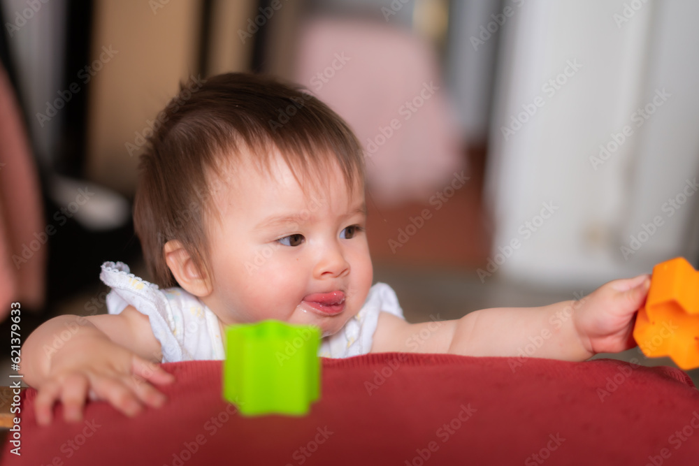 lifestyle home portrait of adorable and beautiful Asian Caucasian mixed baby girl playing on bed with color blocks excited and happy in childhood concept