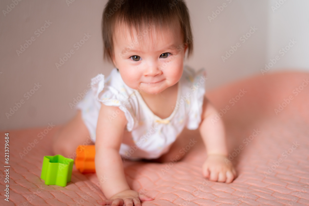lifestyle home portrait of adorable and beautiful Asian Caucasian mixed baby girl playing on bed with color blocks excited and happy in childhood concept