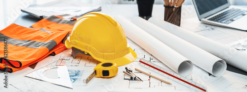 Obraz na plátně Architectural designed building blueprint layout and engineer tool for designing blueprint with contractor project document on engineer workspace table in office with safety helmet or hardhat
