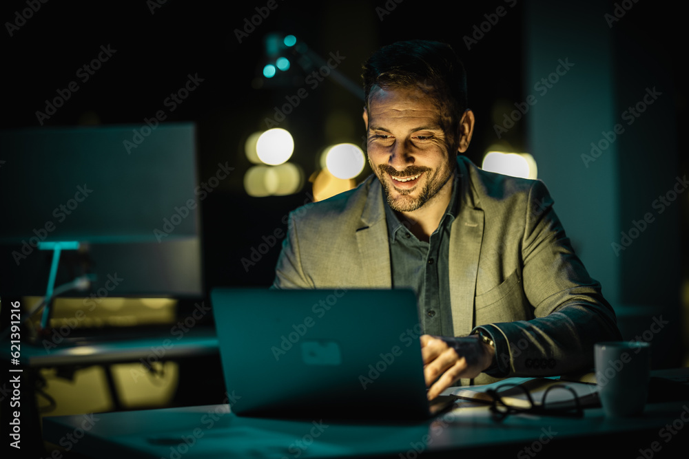 Portrait of handsome businessman working on computer in office late in the evening Portrait of handsome businessman working on computer in office late in the evening