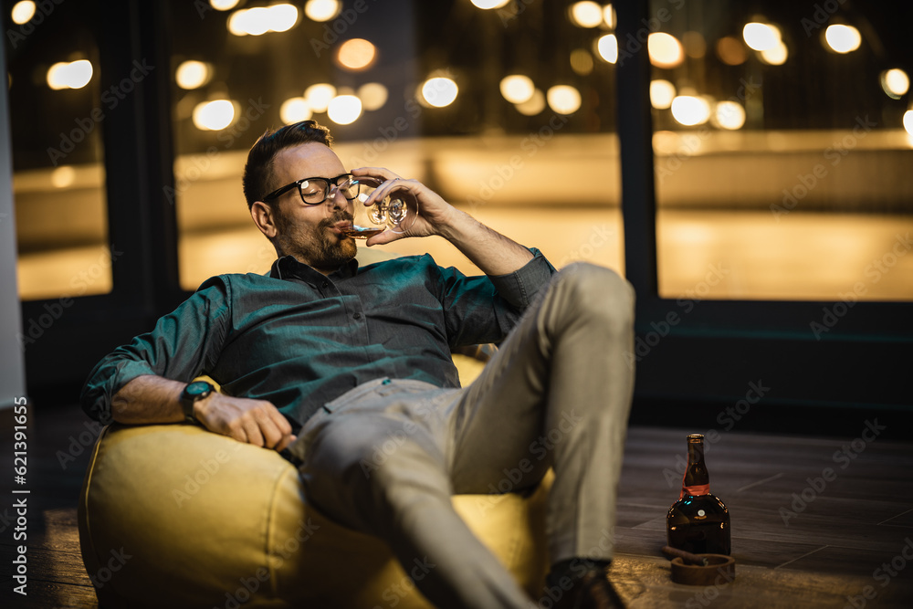 Young businessman sitting in bag chair and drinking cognac after successfull day on work Young businessman sitting in bag chair and drinking cognac after successfull day on work