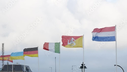 Flags of Spain, Italy, Sicily, Germany, France, Ukraine waving in wind, blue sky background, closeup
