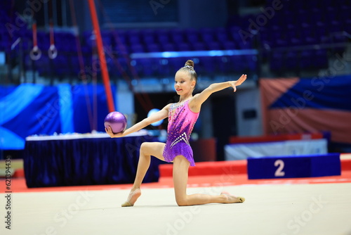 Little girl gymnast, performs various gymnastic and fitness exercises. The concept of childhood and sport, a healthy lifestyle