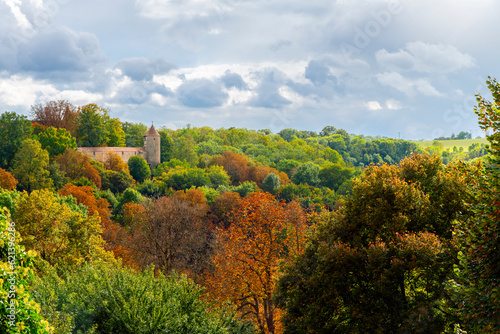 Autumn view with fall colors of a small tower and castle walls in the Bavarian countryside along the outer edge of the walled medieval village of Rothenburg ob der Tauber, Germany.