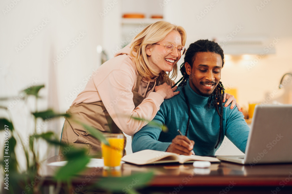 A happy multicultural couple is working together on a project solution together at home. A happy multicultural couple is working together on a project solution together at home.