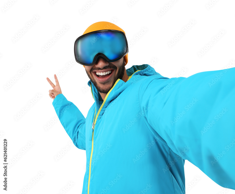 Smiling young man in ski goggles taking selfie and showing peace sign on white background Smiling young man in ski goggles taking selfie and showing peace sign on white background