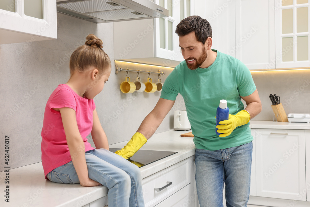 Fototapeta premium Spring cleaning. Father and daughter tidying up stove in kitchen together