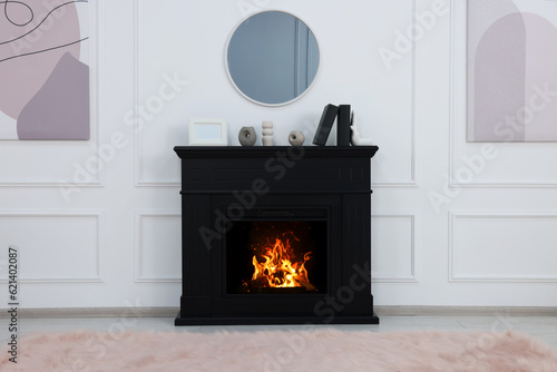 Black stylish fireplace with accessories under round mirror in cosy living room