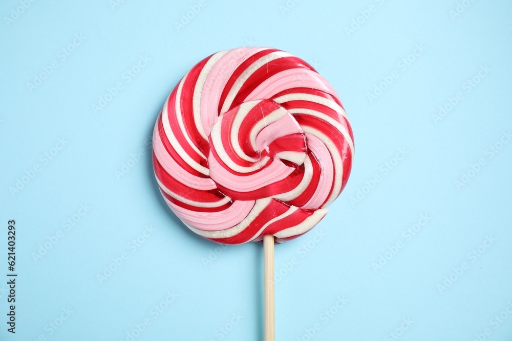 Stick with colorful lollipop swirl on light blue background, top view Stick with colorful lollipop swirl on light blue background, top view