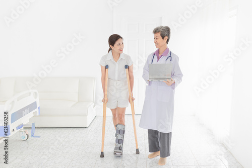 asian patient learning to use crutches with doctor, she wear air cast walking bootwalk, training and rehabilitation, doctor assessment of patient leg