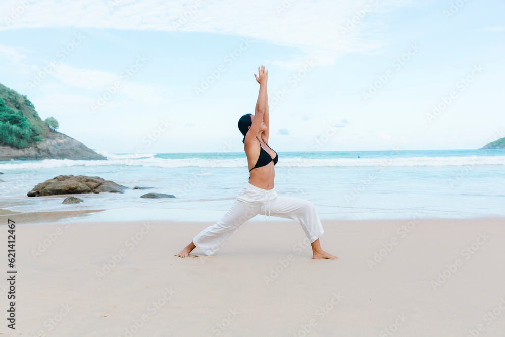 Immersed in a beachside yoga retreat, a happy woman in a bikini finds bliss and harmony as she flows through yoga poses on the sand. Immersed in a beachside yoga retreat, a happy woman in a bikini finds bliss and harmony as she flows through yoga poses on the sand.