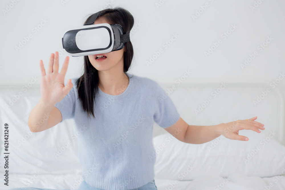 Young asian woman wearing vr headset playing game with excited on bed in the bedroom at home, female using virtual reality or metaverse innovation for simulation 3D, lifestyles and technology concept. Young asian woman wearing vr headset playing game with excited on bed in the bedroom at home, female using virtual reality or metaverse innovation for simulation 3D, lifestyles and technology concept.