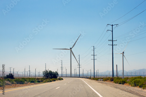California highway, view of wind turbine, electrical poles and electrical wires. Clean and renewable energy. Ecology concept.